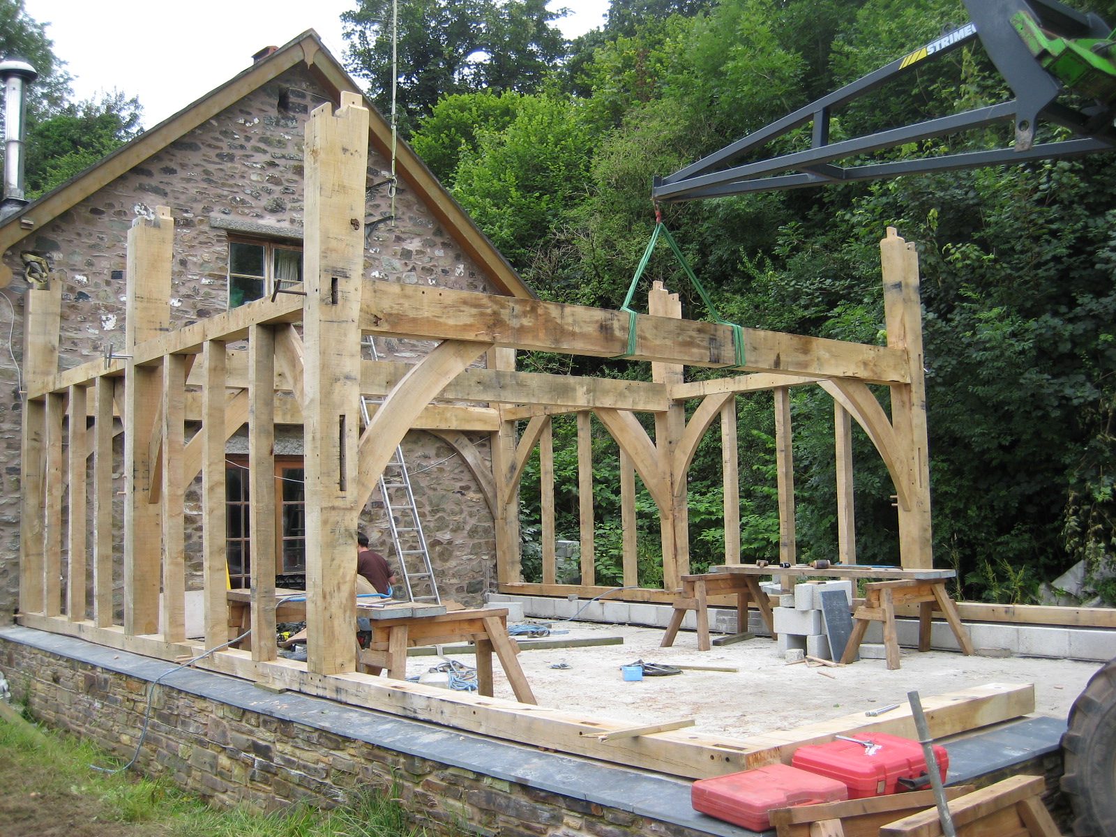 green oak traditional timber frame being built onto the end of a historic barn conversion in devon