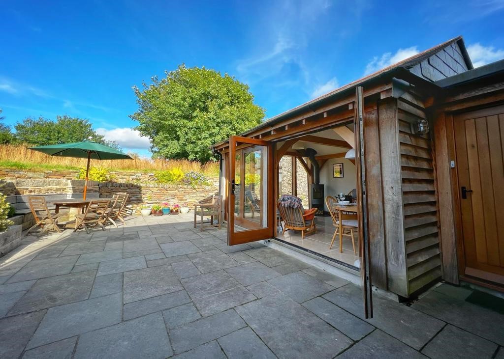 french doors opening onto a sunny patio from a green oak timber framed cabin in the devon countryside