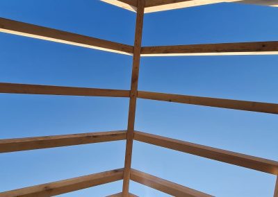 uncovered roof of a timber frame with blue sky above
